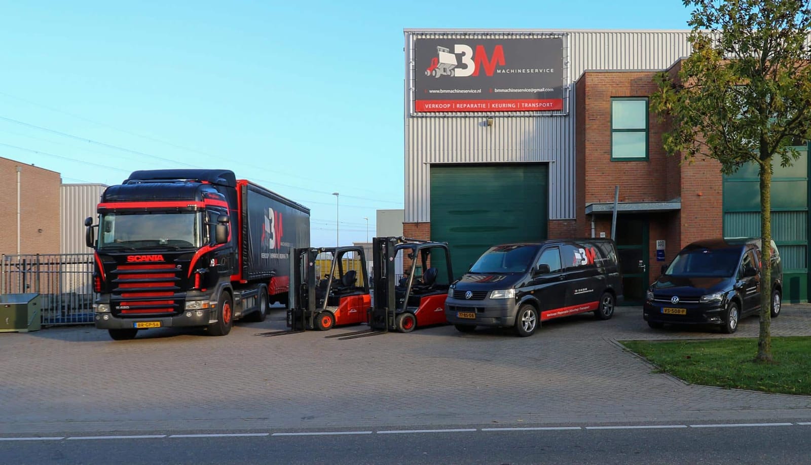 Het bedrijfspand van BM Group aan de Edisonring in Dodewaard, met een Scania trekker, twee Linde heftrucks en twee servicebussen op het voorterrein
